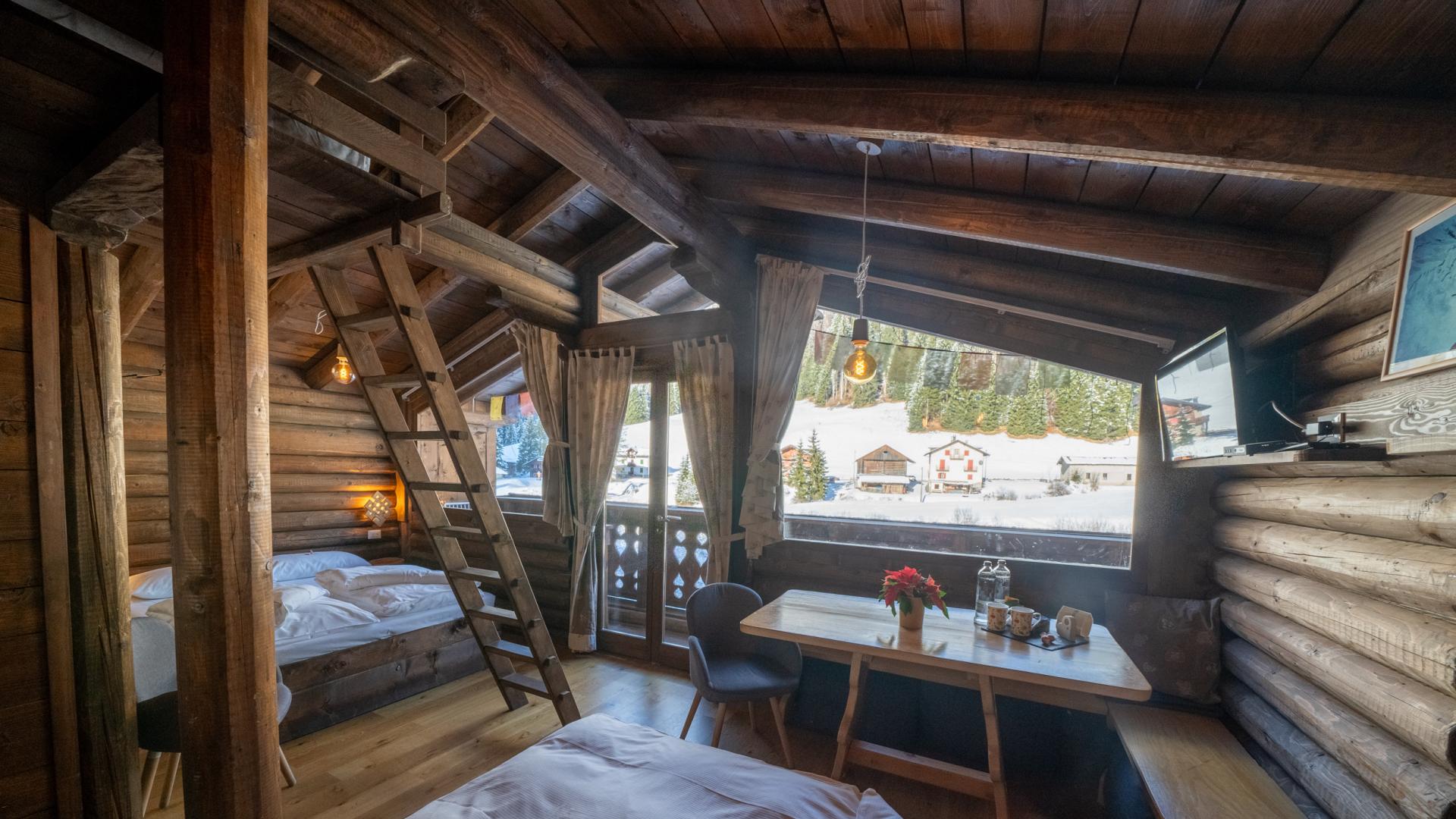 Accogliente baita di montagna con vista innevata e interni in legno.