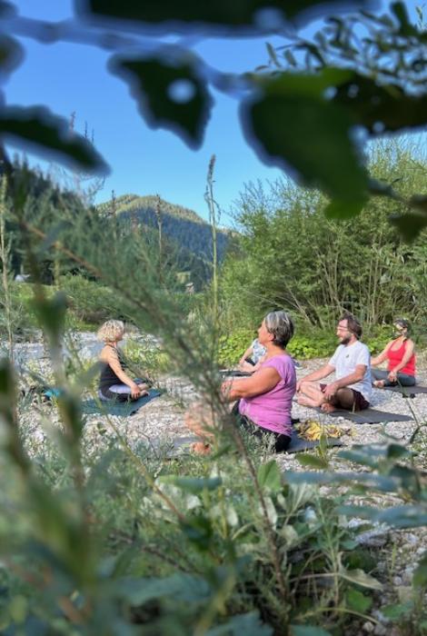 Persone che meditano all'aperto in un ambiente naturale.